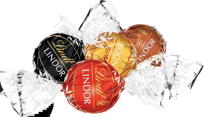 Four Lindtor Lindor chocolates in assorted foil wrappers, including black, gold, red, and brown, arranged on a white background with crumpled clear wrapping paper.